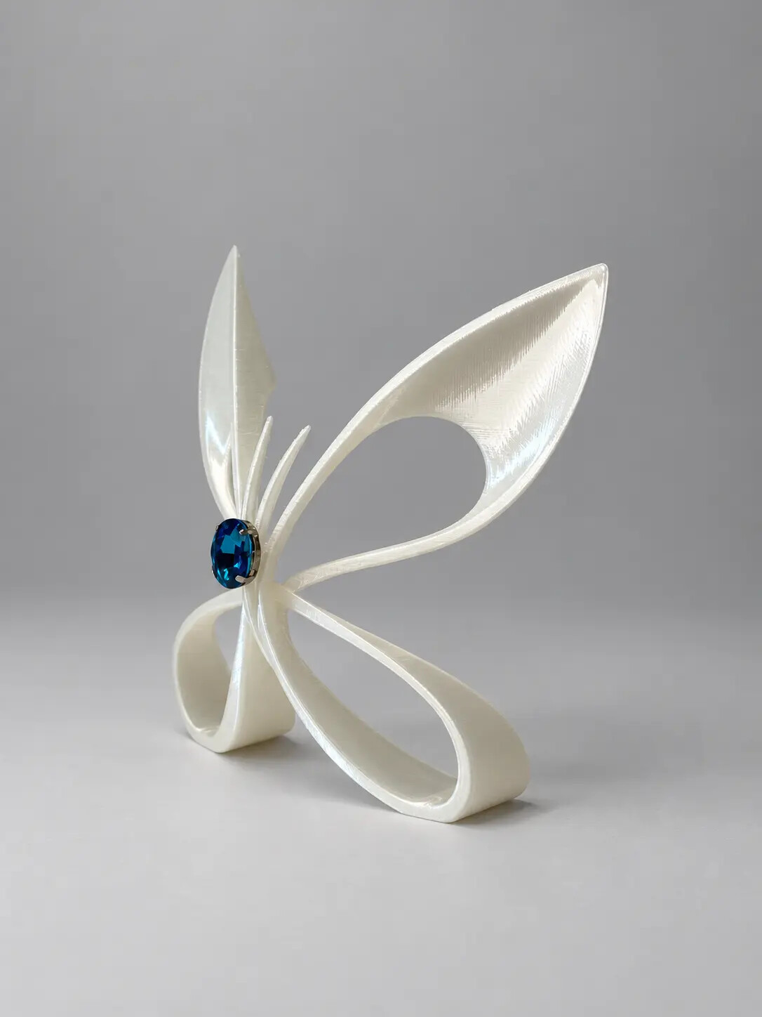 White translucent 3D printed butterfly sculpture with a blue centre stone